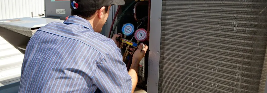 HVAC technician servicing a condenser unit in Edgartown